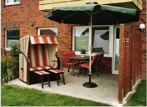 a patio with a table and chairs and an umbrella at Deichwohnung Strandweg 7 in Friedrichskoog-Spitz