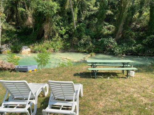 a group of chairs and a picnic table next to a river at Les Mazets de la Cascade in Salernes