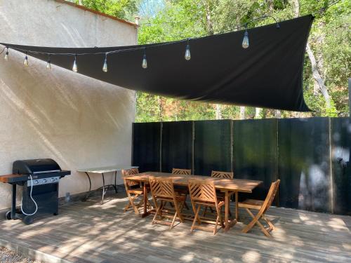 a patio with a table and chairs and a grill at Les Mazets de la Cascade in Salernes