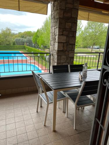 Un patio con mesa y sillas y una piscina. en Appartamento Lago Playa, en Desenzano del Garda