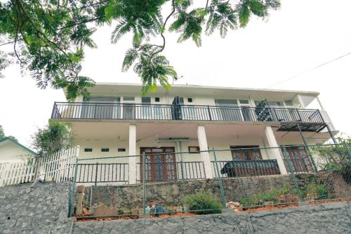 a white house with a fence in front of it at Dream Stay Green in Nuwara Eliya