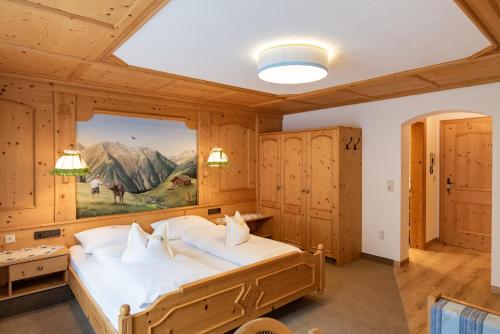 a bedroom with a large bed with a painting on the wall at Landhaus Marion in Holzgau