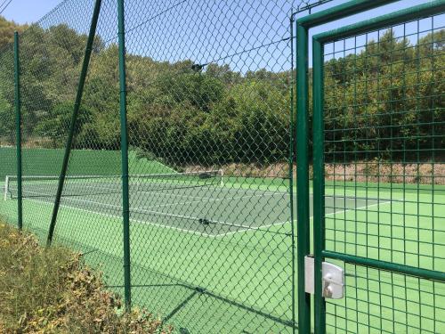 a view of a tennis court through a fence at Les Mazets de la Cascade in Salernes