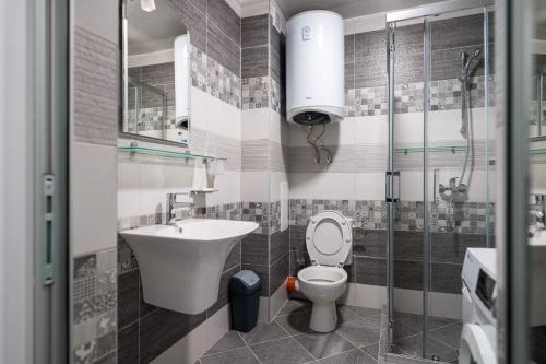 een badkamer met een toilet, een wastafel en een douche bij Апартамент Тюркоаз in Varna