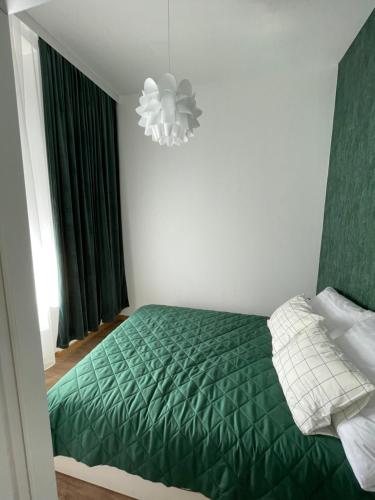 a bedroom with a green bed and a chandelier at Mini apartament Ostróda in Ostróda