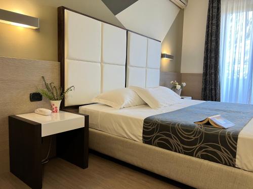 a bedroom with a bed and a nightstand with a bed sidx sidx sidx sidx at Hotel Gardenia in Romano Canavese