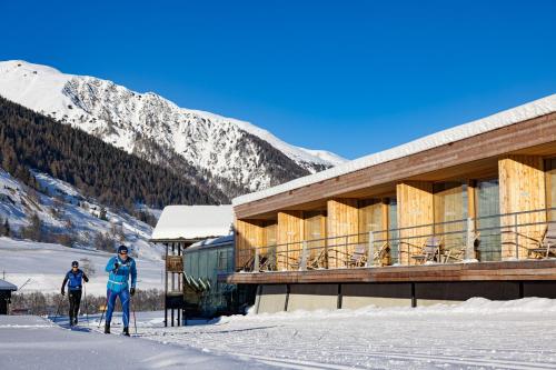 two people on skis in the snow in front of a building at Hotel Glocke in Reckingen - Gluringen