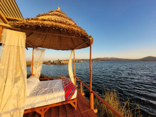 ein Boot mit einem Bett und einem Sonnenschirm auf dem Wasser in der Unterkunft TITICACA JALTAWI LODGE in Puno