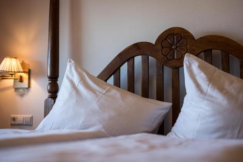 a bed with white pillows and a wooden head board at Hotel Finkennest - Panoramic Garden Resort in Schenna