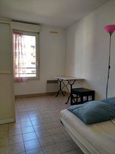 une chambre avec un lit, une table et une fenêtre dans l'établissement Appartement F2 à 50 m de la plage, à Nice