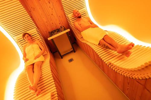 a woman and a man sitting on beds in a room at Hotel Glocke in Reckingen - Gluringen