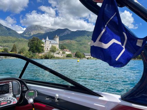 ein Boot auf einem See mit einem Schloss im Hintergrund in der Unterkunft Entre Lac d'Annecy et montagnes, golf et parapente à pieds in Talloires