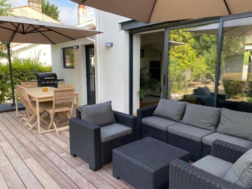 une terrasse avec une table, des chaises et un parasol dans l'établissement Villa au calme dans un écrin de verdure, à Aytré