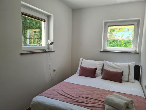 a small bedroom with a bed with two windows at Agava sunset in Ankaran