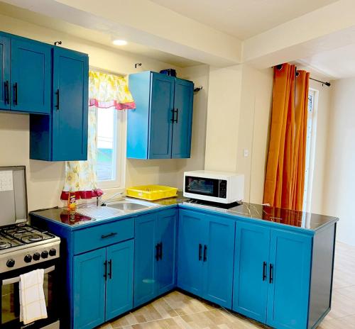 niebieska kuchnia z niebieskimi szafkami i kuchenką mikrofalową w obiekcie The Golden Inn w mieście Marigot