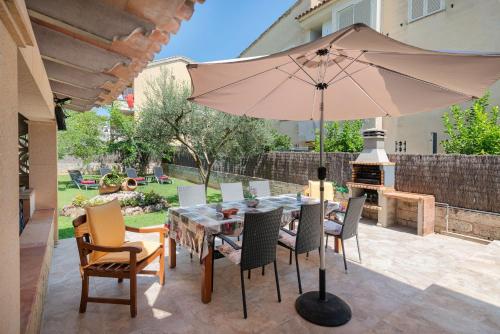 a patio with a table and chairs and an umbrella at Villa Roses - Alcúdia in Alcudia