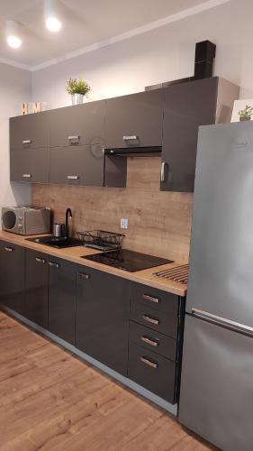 a kitchen with black cabinets and a white refrigerator at Apartament Tuwima Park in Ełk