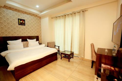 a bedroom with a bed and a table and a television at Hotel The Spades in Zirakpur