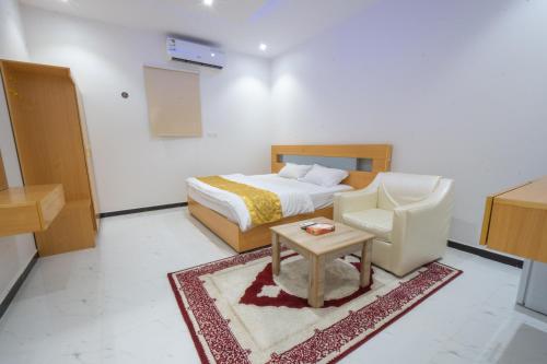 a bedroom with a bed and a chair and a table at شقق ابيات الشمال للشقق المخدومة in Rafha