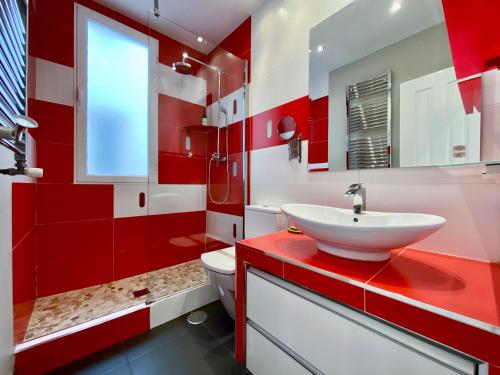 baño rojo y blanco con lavabo y aseo en Charming Blasco de Garay - Estancias Temporales, en Madrid