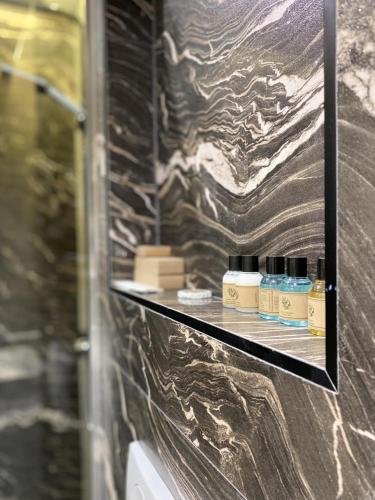 a bathroom with a shelf with four bottles of soap at Marinus Hotel in Ulcinj