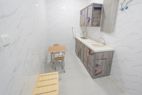a white bathroom with a sink and a stool at شقق ابيات الشمال للشقق المخدومة in Rafha