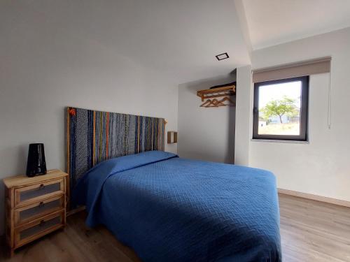 Un dormitorio con una cama azul y una ventana en Miradouros da Aldeia, en Sabugueiro