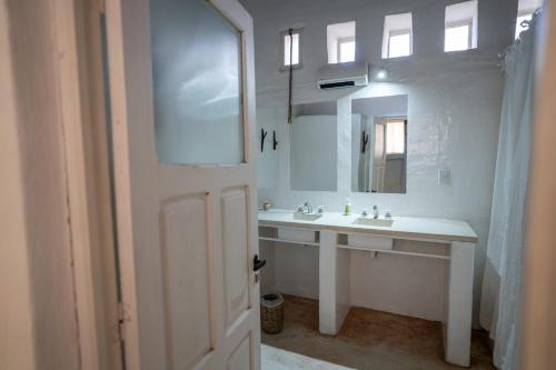 Baño blanco con lavabo y espejo en Sala de Payogasta en Payogasta