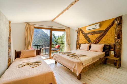 two beds in a room with a balcony at MANZARA BUNGALOW in Fethiye