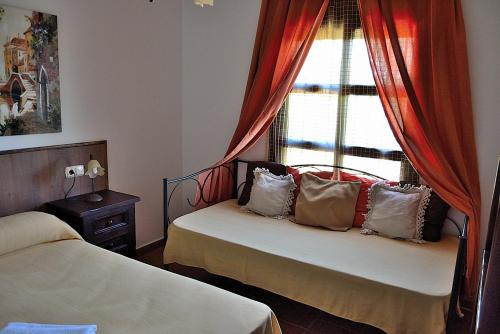 a bedroom with two beds and a window with red curtains at CASA PEPE Y MARI CON PISCINA in Alora