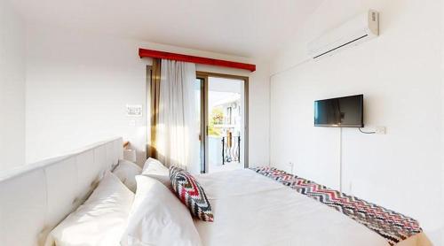 a white living room with a couch and a tv at Templos Homes in Kérynia