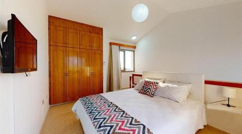 a bedroom with a bed with a television and a cabinet at Templos Homes in Kérynia