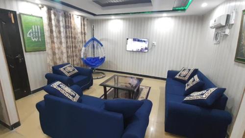 a living room with blue chairs and a glass table at Heaven Heights Apartment in Murree