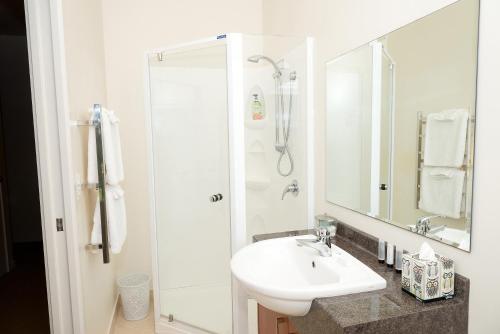 a white bathroom with a sink and a shower at By The Park B & B in Whangarei