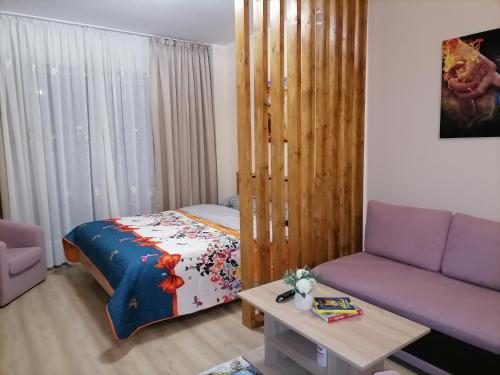 sala de estar con cama y sofá púrpura en Apartament NyX en Floreşti