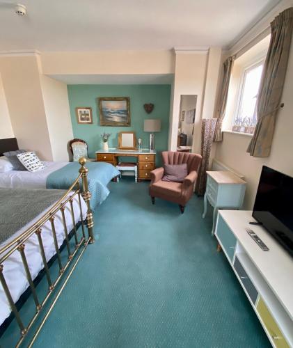 a bedroom with a bed and a desk and a chair at Mariners Hotel in Seaton
