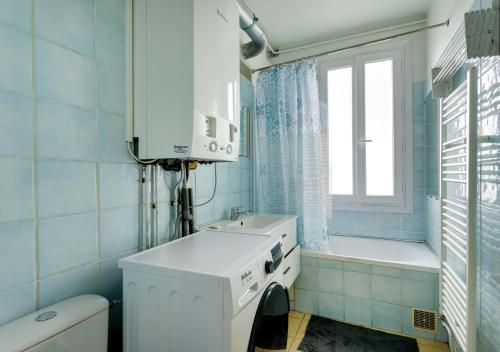 baño azul con lavadora y ventana en Au PIED de la GARE aux PORTES de PARIS, en Vitry-sur-Seine
