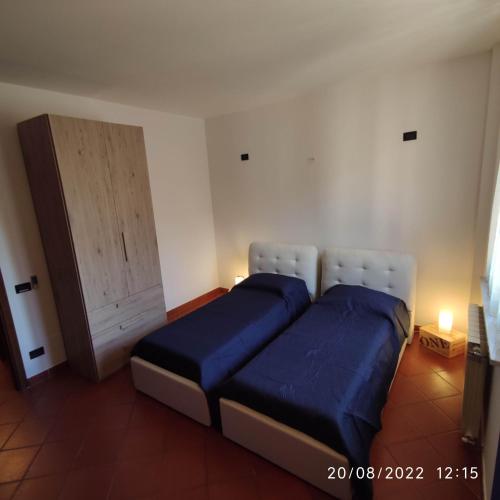 a bedroom with two beds with blue sheets and a door at M & M Pinzi Suite Apartment in Montepulciano Stazione