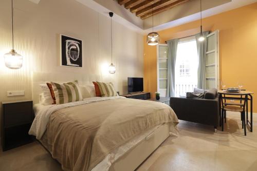 a bedroom with a bed and a chair and a television at GRUND SUITES GALLERY by FreshApartments in Málaga