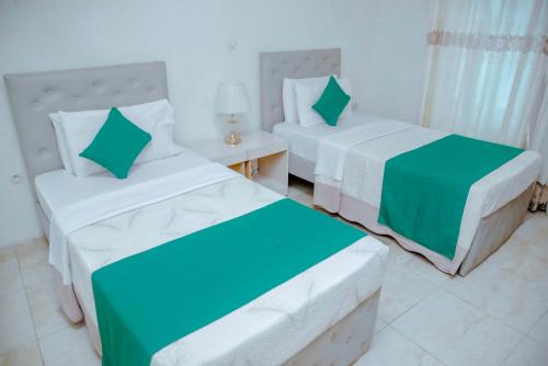 a bedroom with two beds and a night stand with a table at Martin Aviator Hotel in Kigali