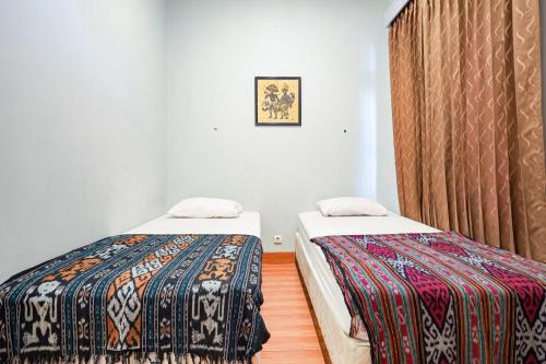 2 camas en una habitación con cortina en Hope Hotel Yogyakarta en Yogyakarta
