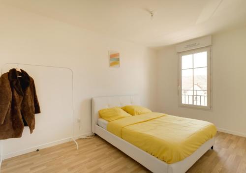 1 dormitorio con 1 cama con sábanas amarillas y ventana en Au CALME entre DISNEY et PARIS, en Villiers-sur-Marne