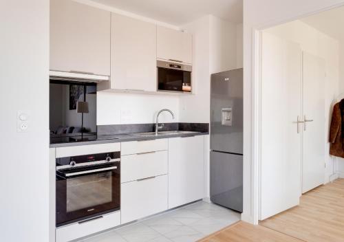 a kitchen with white cabinets and a stainless steel refrigerator at Au CALME entre DISNEY et PARIS in Villiers-sur-Marne