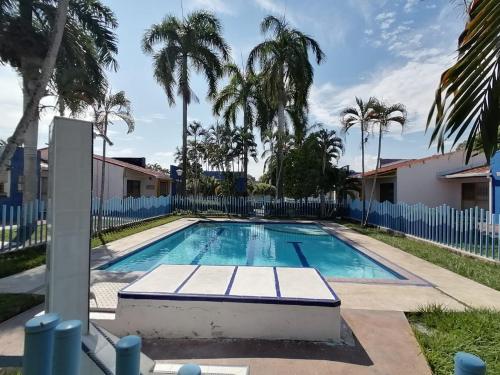 a swimming pool with palm trees and a fence at Precioso alojamiento con 6 piscinas en conjunto cerrado in Espinal