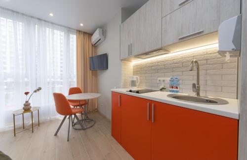 a kitchen with orange cabinets and a sink and a table at MYFREEDOM Апартаменти метро Сирець in Kyiv