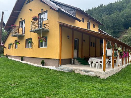a yellow house with a table and chairs in front of it at Casa Natalia Raisa Arieșeni in Arieşeni