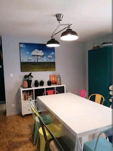 une salle à manger avec une table et des chaises blanches dans l'établissement Maison au calme à 10 min de Noirmoutier, à Saint-Urbain