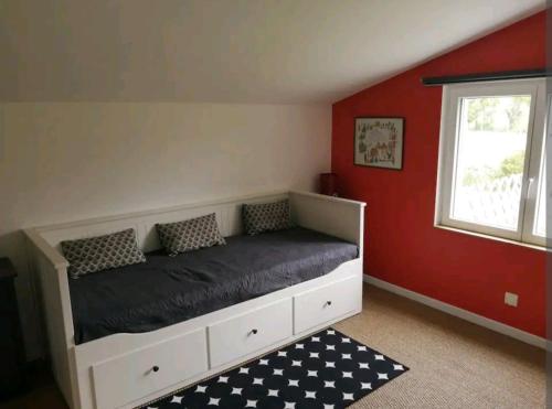 Ce lit se trouve dans une chambre dotée d'un mur rouge. dans l'établissement Maison au calme à 10 min de Noirmoutier, à Saint-Urbain