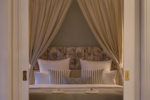 a bedroom with a canopy bed with white pillows at Weissenhaus Private Nature Luxury Resort in Weißenhaus