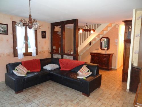 a living room with a black leather couch and stairs at Au plaisir des pêcheurs - Les Sceps in Genouilly